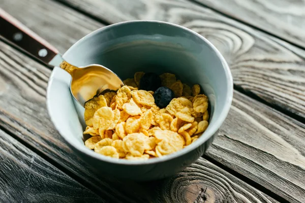 Breakfast with corn flakes and blueberries on wooden table