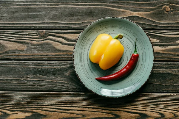 黄色のベル 木製テーブルの上皿に赤唐辛子  — 無料ストックフォト