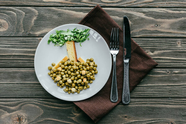 Здоровый ужин на тарелке со столовыми приборами на салфетке
