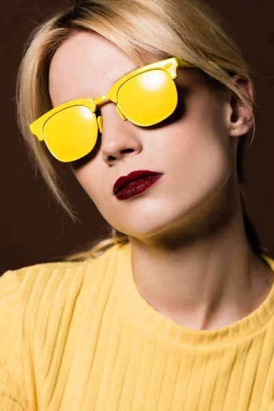 ブラウンに分離された黄色のサングラスを身に着けている美しい金髪少女のクローズ アップの肖像画  — 無料ストックフォト