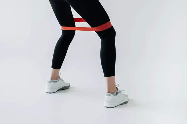 partial view of exercising with rubber tape on grey background