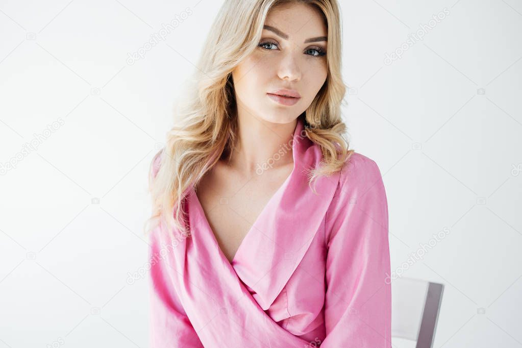 portrait of attractive young woman in pink blouse posing on white background