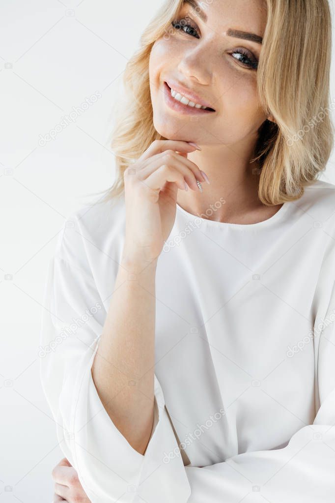 portrait of beautiful smiling woman in white clothing looking at camera on white background