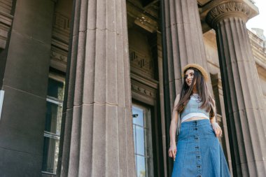 düşük açılı görünümü sütunları duran ve uzağa arıyorsunuz şapkalı gülümseyen kız