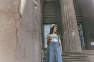 merdivenlerin üzerinde duran ve uzağa arıyorsunuz kitap ve elma tutan genç kadın düşük açılı görünümü 