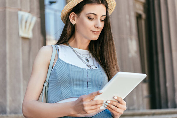 beautiful smiling young woman using digital tablet on street