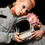 Astronauta femenina sensual en traje espacial con flor de peonía y casco, aislado en negro