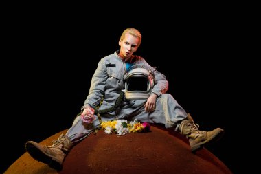 çiçek ve gezegen üzerinde oturan kask ile uzay giysisi içinde çekici spacewoman 