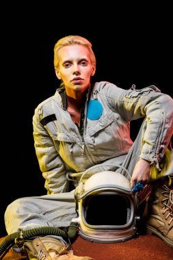 gezegen üzerinde oturan kask ile uzay giysisi içinde çekici astronot