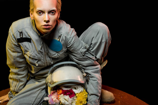 cosmonaut in spacesuit with flowers in helmet sitting on planet 