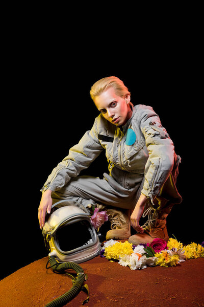 stylish cosmonaut in spacesuit with flowers and helmet sitting on planet 