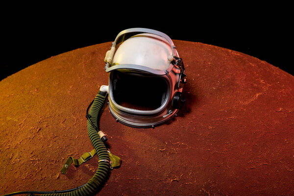 helmet from spacesuit lying on red planet in black cosmos
