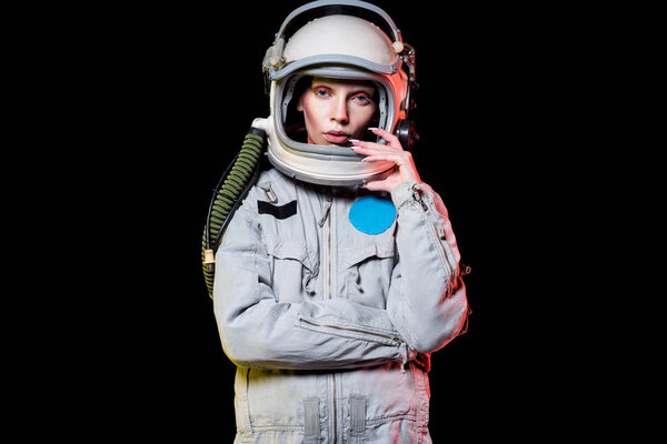 attractive female astronaut in spacesuit and helmet isolated on black