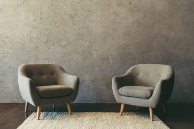 Beyaz halı üzerinde duran koltuklar ile modern oda içi