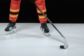 oříznuté záběr profesionální sportovec v brusle hrát lední hokej na černém pozadí