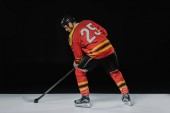 zadní pohled na profesionální sportovec, hraje lední hokej na černém pozadí  