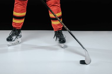 cropped shot of professional sportsman in skates playing ice hockey on black clipart