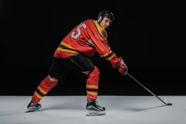 young professional sportsman playing ice hockey on black   clipart