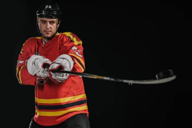 professional hockey player holding hockey stick isolated on black clipart
