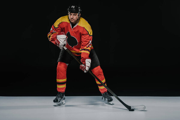 full length view of professional young ice hockey player playing hockey on black  
