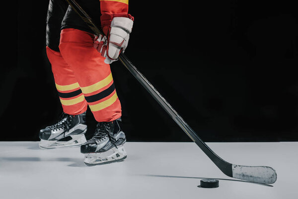 low section of professional sportsman playing hockey on black  