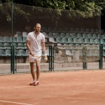 Guapo jugador de tenis de estilo retro durante el juego en la cancha de tenis