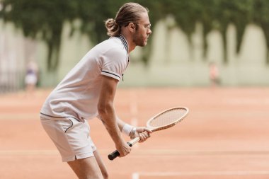 yakışıklı tenis oyuncusu oyun için hazır raket Tenis Kortu yönü ile yan görünüm