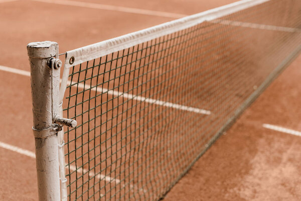 brown tennis court with tennis net and marking lines