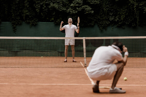 теннисист в стиле ретро показывает жест "да" после победы на теннисном корте
