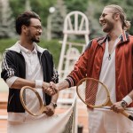 Happy retro styled tennis players shaking hands at tennis court