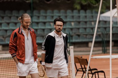 Tenis Kortu, raketleri ile yürüme yakışıklı retro tarz tenis oyuncuları  