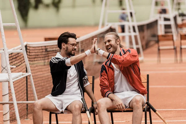 微笑复古风格的网球运动员在网球场给予高五 — 图库照片