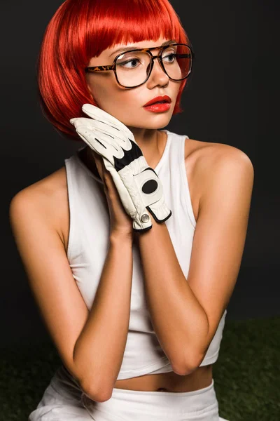 赤いおかっぱ散髪ゴルフ グローブとグレーによそ見スタイリッシュな眼鏡を持つ魅惑的な若い女性 — ストック写真