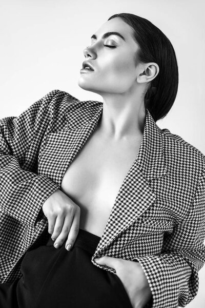 seductive half naked woman posing in retro jacket, isolated on grey, black and white