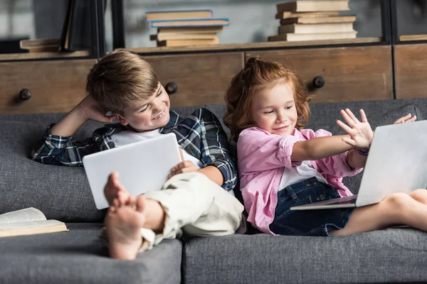 Fratellino Sorella Che Usano Dispositivi Digitali Mentre Rilassano Sul Divano — Foto Stock