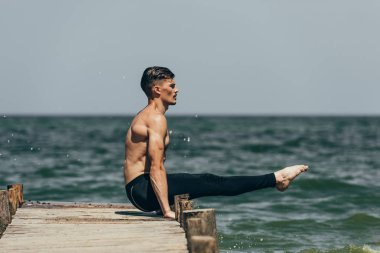 gömleksiz yakışıklı iskelede yoga ve iş kolu denge pratik