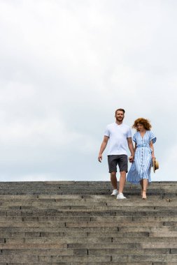 low angle view of redhead couple holding hands and walking on stairs  clipart