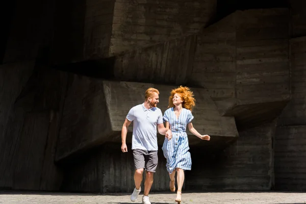 Smiling Redhead Couple Holding Hands Running City Street — Free Stock Photo