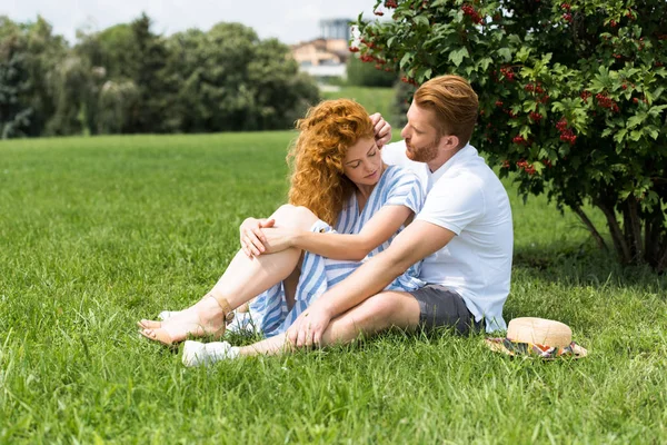 红头发的人触摸女朋友的头发在草地上公园 — 免费的图库照片