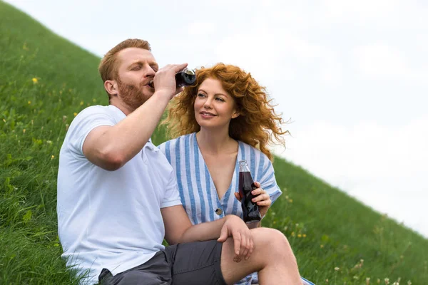 Redhead Man Closed Eyes Drinking Soda Bottle Smiling Girlfriend Grassy — Stock Photo, Image