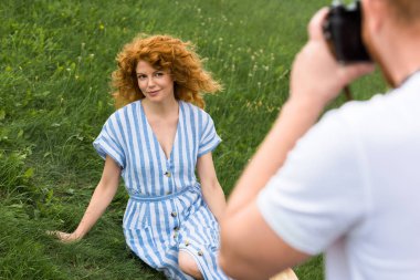 Kızıl saçlı kadın otsu çayır üzerinde gülümseyen fotoğrafını adamın kısmi görünümü