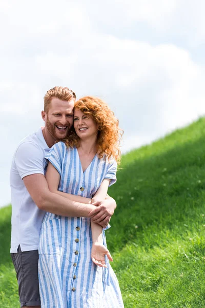 Ler Rödhårig Man Omfamnar Flickvän Bakifrån Gräsbevuxen Kulle — Stockfoto