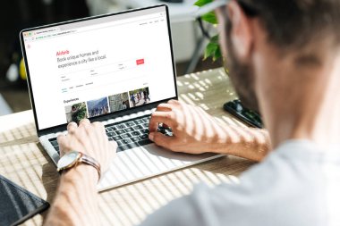 arkadan görünüşü ile airbnb Web sitesinde ekran dizüstü bilgisayar kullanan adam