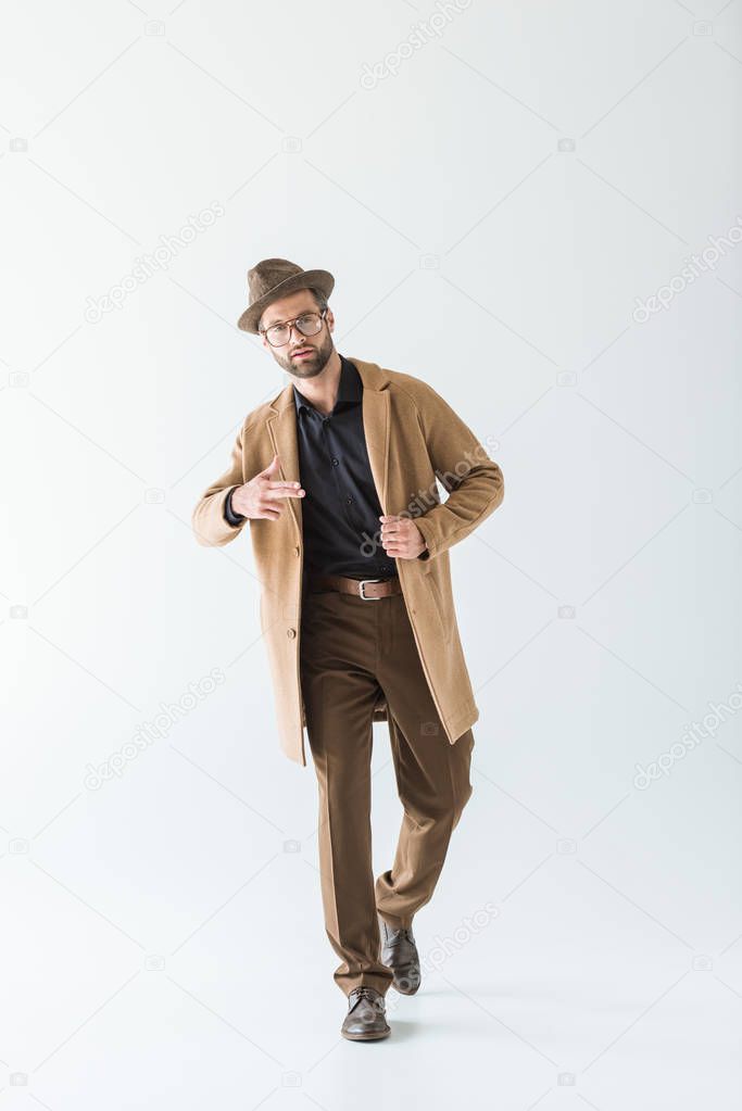 fashionable man posing in brown autumn coat and hat, isolated on white