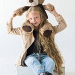 Full length view of beautiful stylish kid holding teddy bear and smiling at camera isolated on white