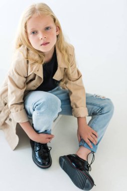 uzun kıvırcık saçlı oturan ve üzerinde beyaz izole kamera bakarak şık çocuğun yüksek açılı görünüş