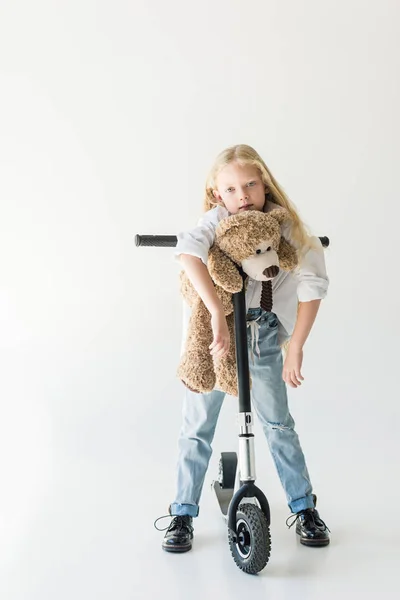 Adorable Niño Apoyado Scooter Con Osito Peluche Mirando Cámara Blanco — Foto de stock gratis