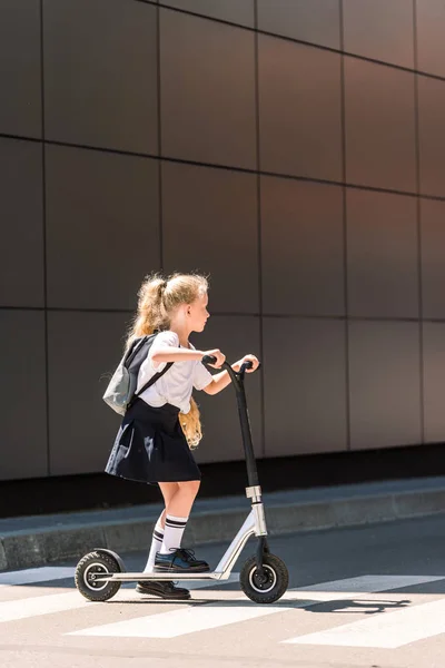 Widok Boku Adorable Little Uczennica Plecaka Jazda Skuterem Ulicy — Zdjęcie stockowe