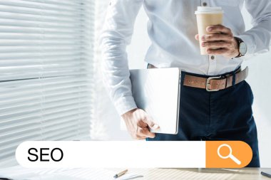 Seo arama çubuğu ile gitmek geliştirici laptop ve kahve tutan kırpılmış görünümü