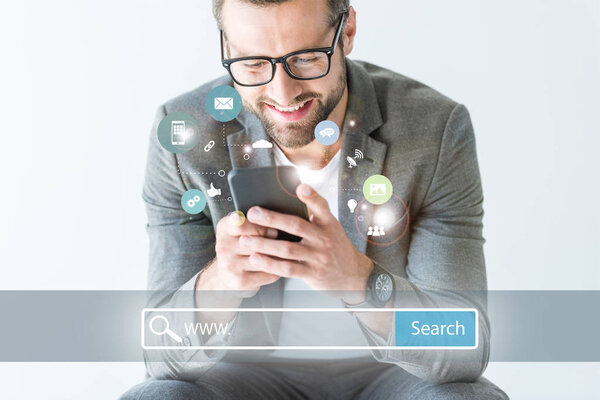 smiling SEO developer in gray suit using smartphone, isolated on white with website search bar and icons